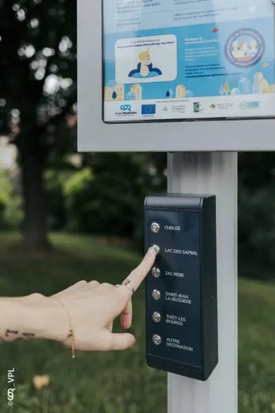 Main appuyant sur une borne de covoiturage pour sélectionner une destination